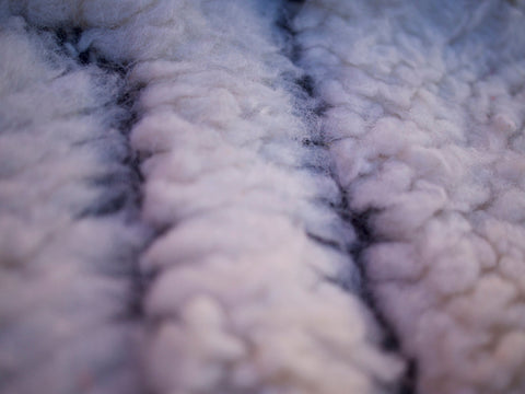 Close-up detail of a striped pattern and fluffy texture on a black and white rug.
