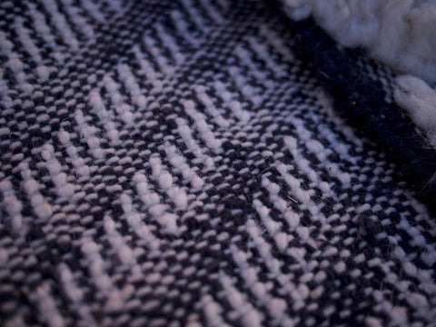 Close-up detail of a woven pattern and textured surface on a black and white rug.