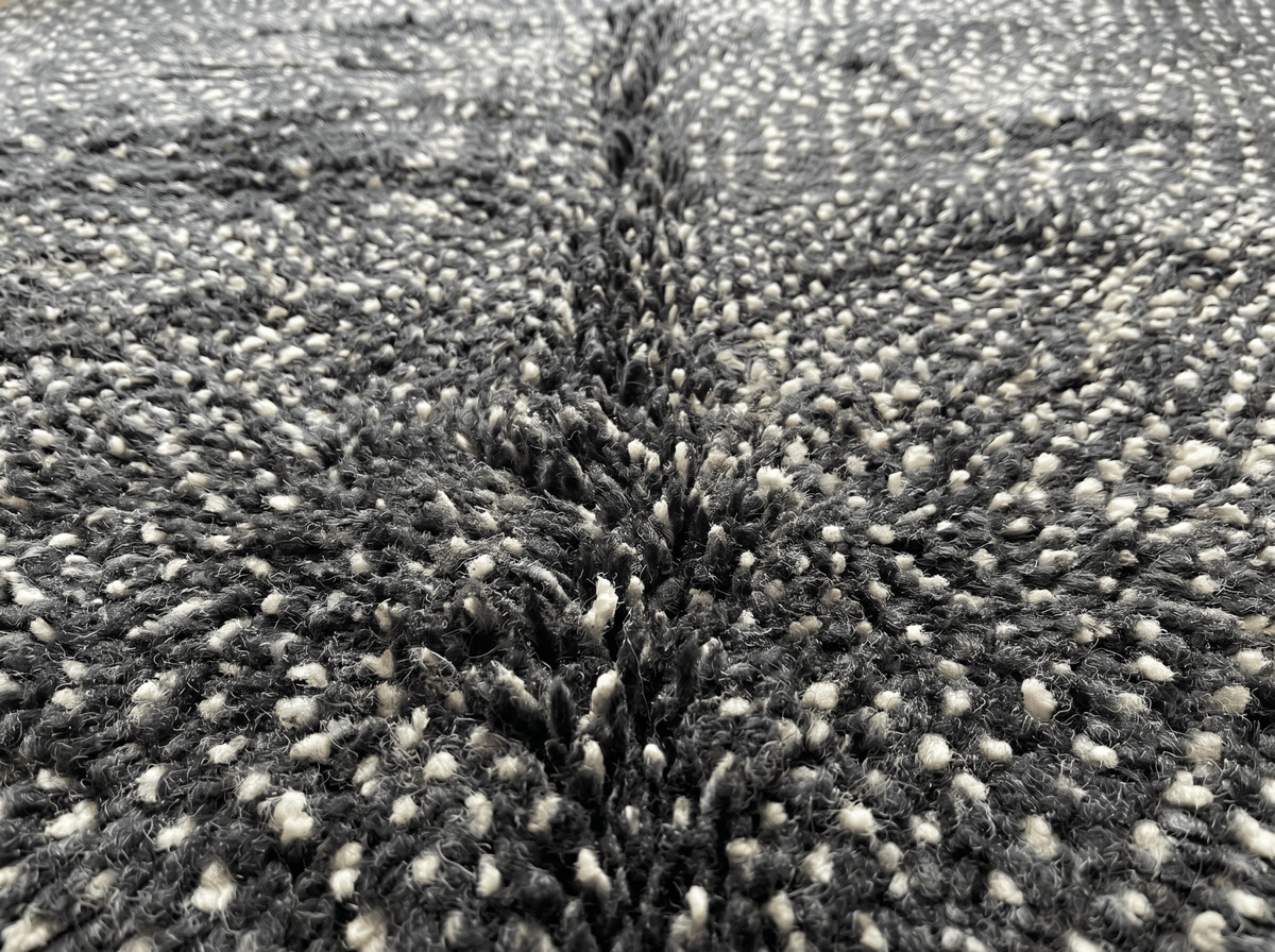 Detail view of a black Moroccan rug highlighting its woven pattern and fringe.