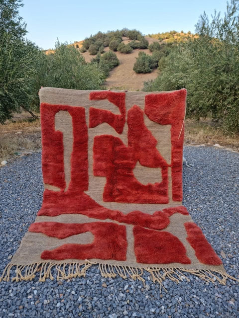 Lifestyle shot of a blood red Moroccan rug featuring a geometric pattern and fringe edges.
