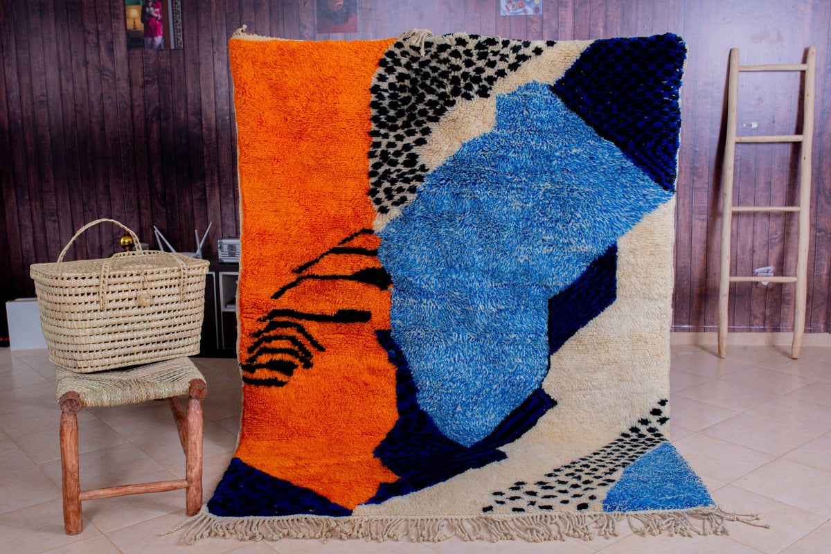 Lifestyle view of a blue Moroccan rug featuring geometric designs and fringe edges.