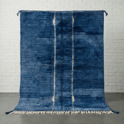 Front view of a blue Moroccan rug featuring a geometric pattern on a studio background.