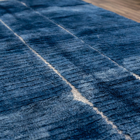 Close-up detail of a blue Moroccan rug with a textured surface displayed in a studio setting.