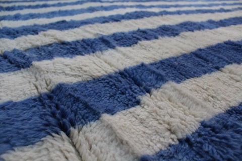 Detail view of a blue striped Moroccan rug with a textured surface.