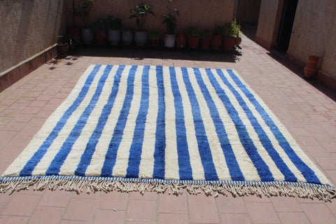 Lifestyle view of a blue striped rug with fringed edges.