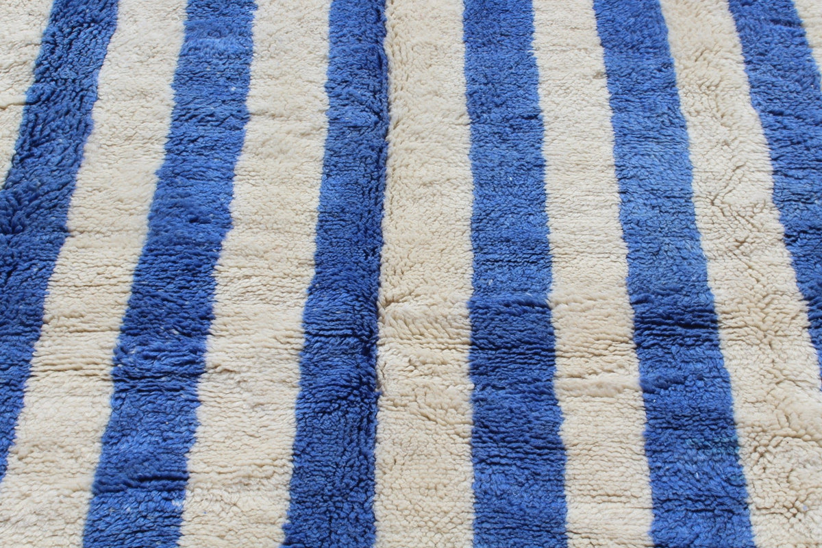 Detail shot of a blue striped Moroccan rug emphasizing its textured surface.