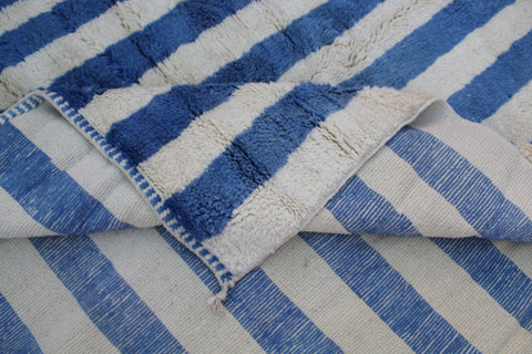 Detail view of a blue striped Moroccan rug highlighting its textured fabric.