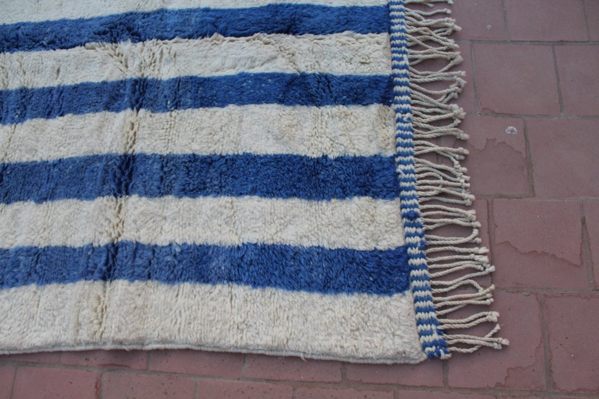 Detail view of a blue striped rug highlighting its fringe edges.