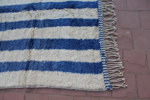 Detail view of a blue striped rug highlighting its fringe edges.