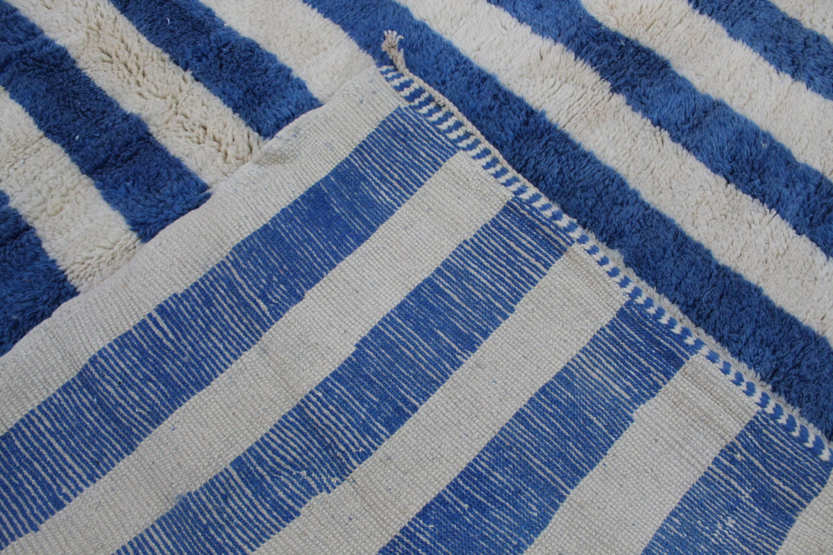 Detail view of a blue striped Moroccan rug with thick stripes and woven texture.