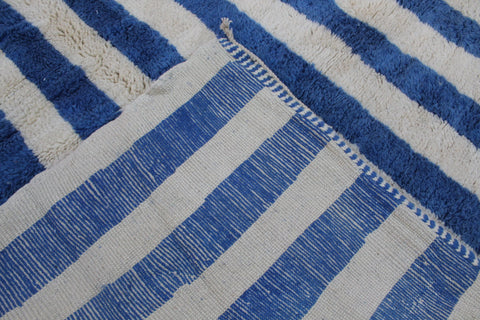 Detail view of a blue striped Moroccan rug with thick stripes and woven texture.