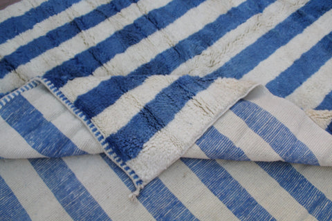 Close-up detail of a blue striped rug with folded edges.