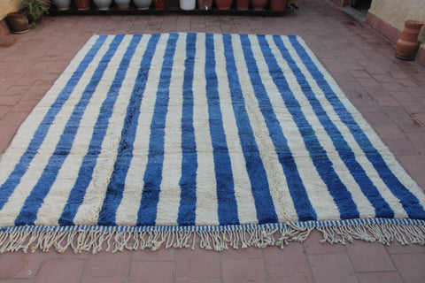 Lifestyle view of a blue striped Moroccan rug with a textured surface.