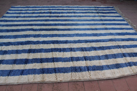 Lifestyle shot of a blue striped Moroccan rug in a natural setting.