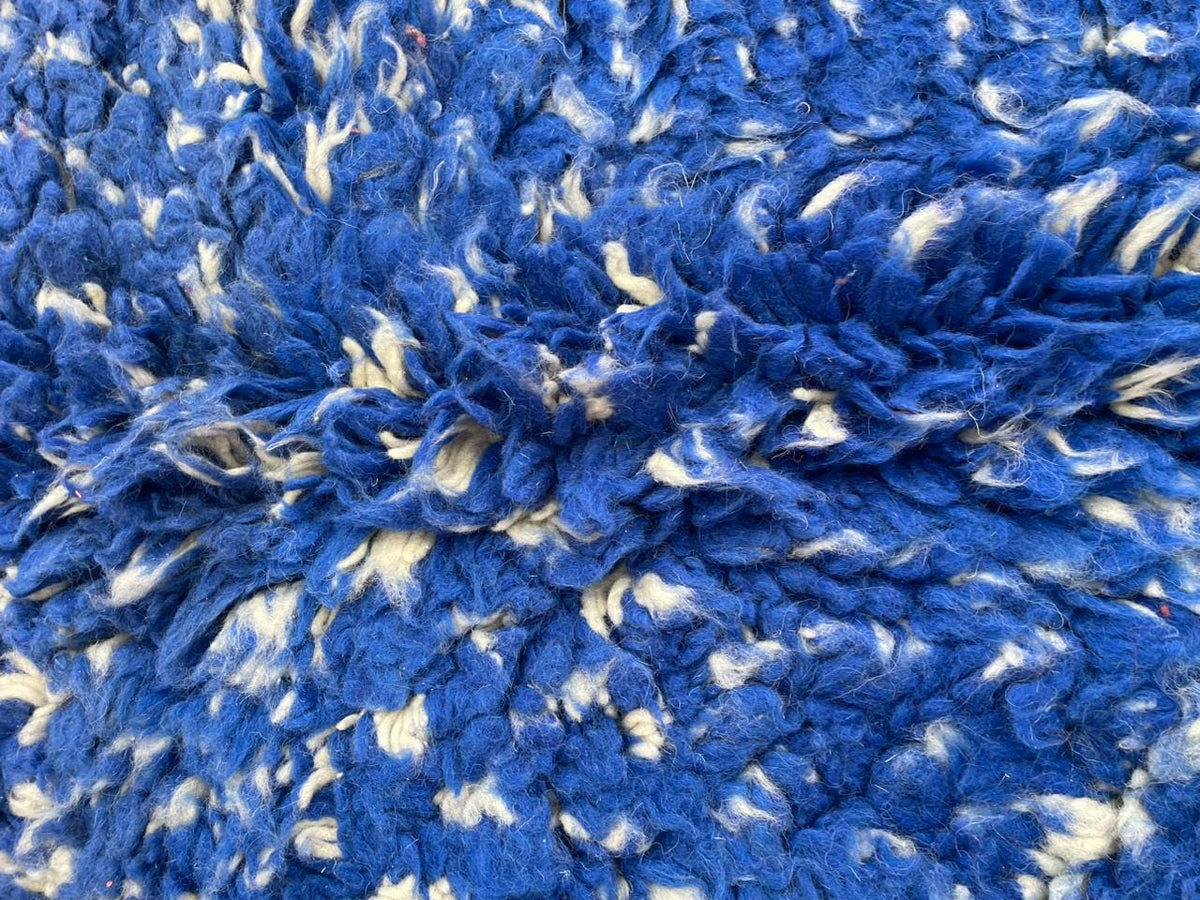 Close-up of stripe patterns on the blue vintage Moroccan rug with a neutral backdrop.