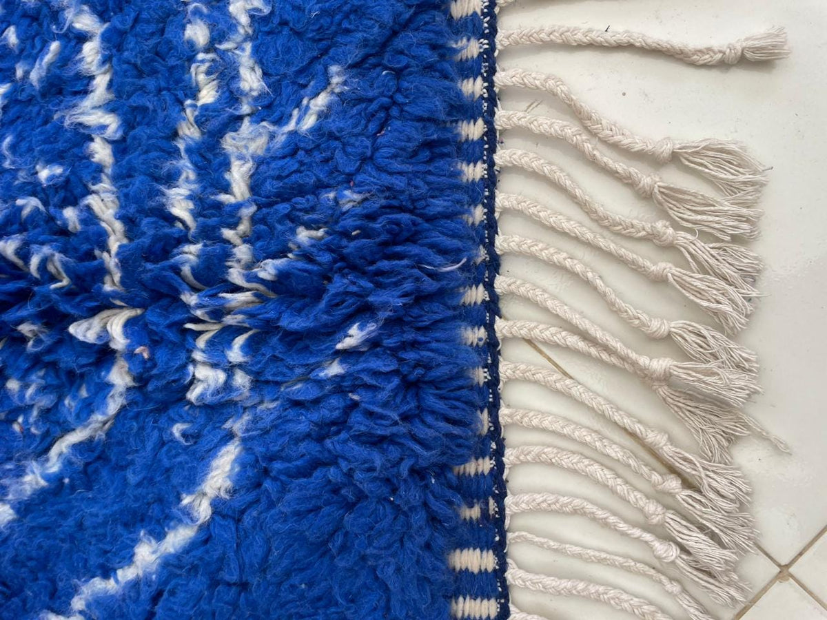 Detail view of the fringe edges and tribal pattern on the blue vintage Moroccan rug.