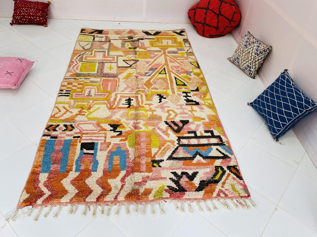 Close-up detail of the edge of the orange abstract Moroccan rug highlighting its fringe.