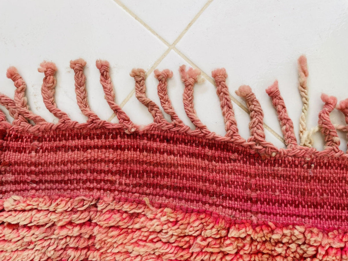 Close-up of the fringe detail and woven texture in red and cream.
