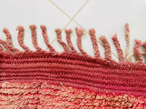 Close-up of the fringe detail and woven texture in red and cream.