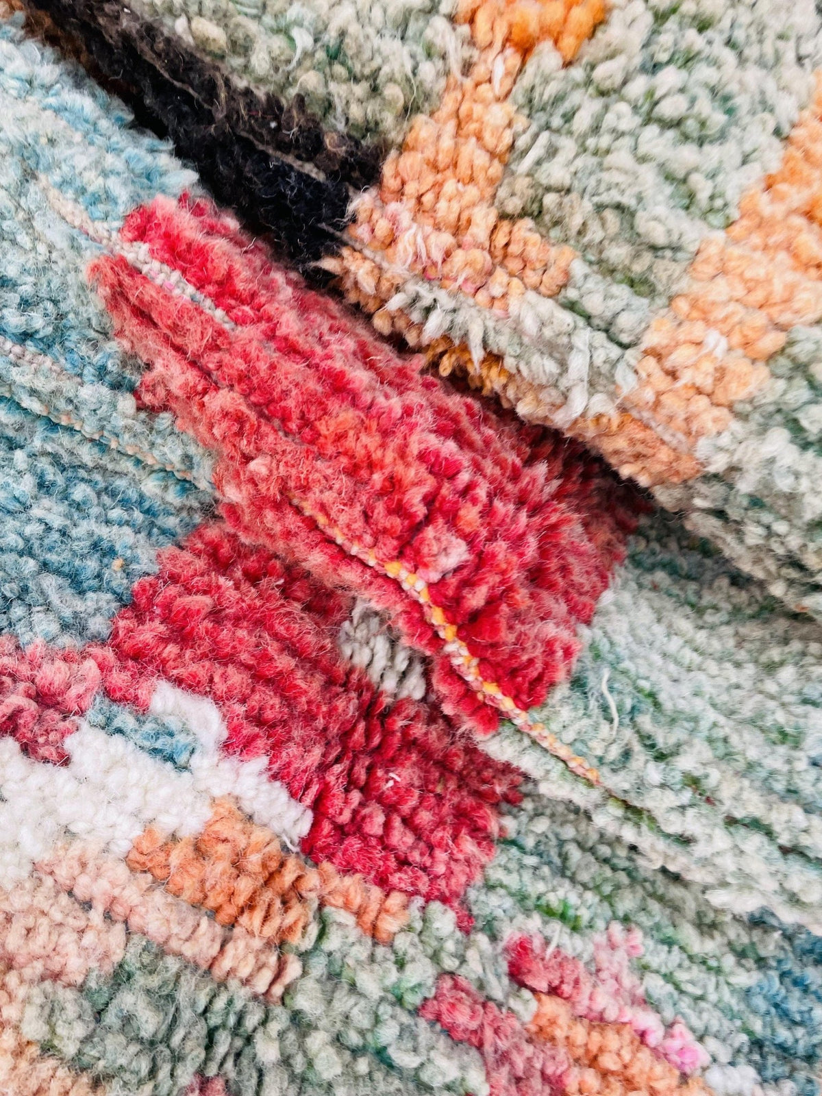 Close-up detail of an orange and blue Moroccan rug showcasing its textured weave and colorful patterns.
