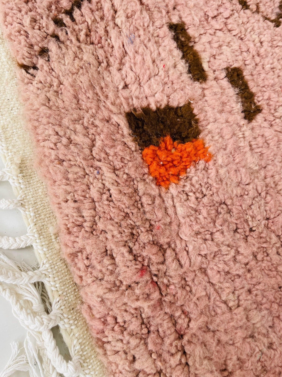 Close-up detail of the textured fibers of the orange geometric Boujaad Moroccan rug highlighting colorful accents.