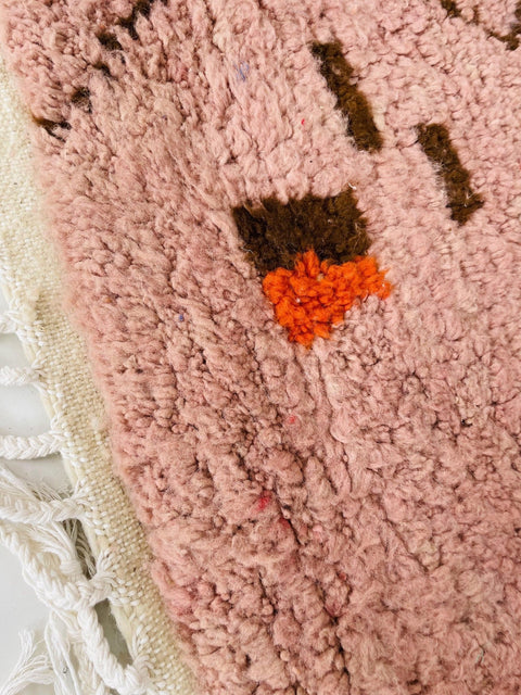 Close-up detail of the textured fibers of the orange geometric Boujaad Moroccan rug highlighting colorful accents.