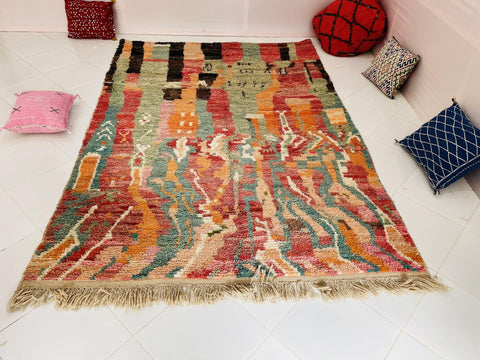 Close-up detail of an orange Moroccan rug featuring fringe detail and woven texture.