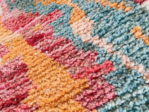 Close-up detail of an orange Moroccan rug displaying an abstract pattern.