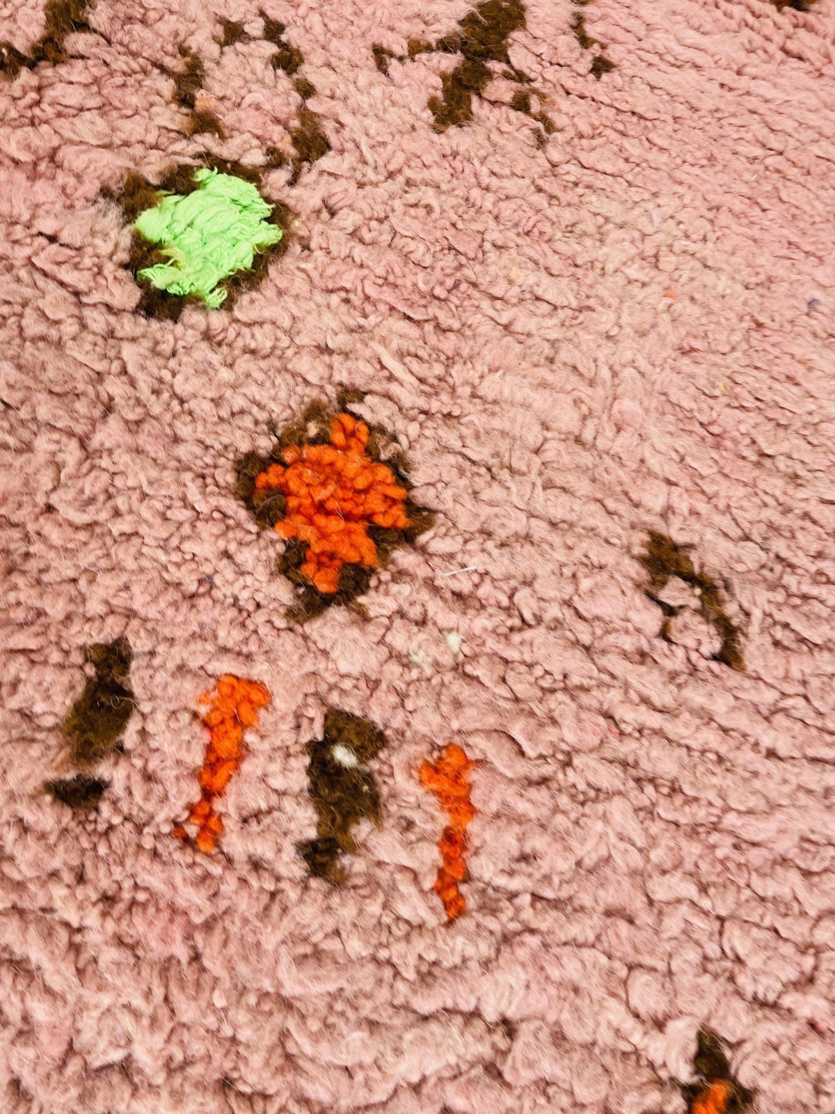 Close-up image of the orange geometric Boujaad Moroccan rug featuring abstract patterns with pink and green accents.