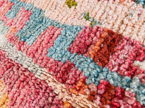 Close-up detail of an orange Moroccan rug with an abstract pattern and pink accents.
