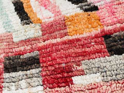 Detail shot of the Moroccan rug displaying an abstract pattern in orange, red, and black.