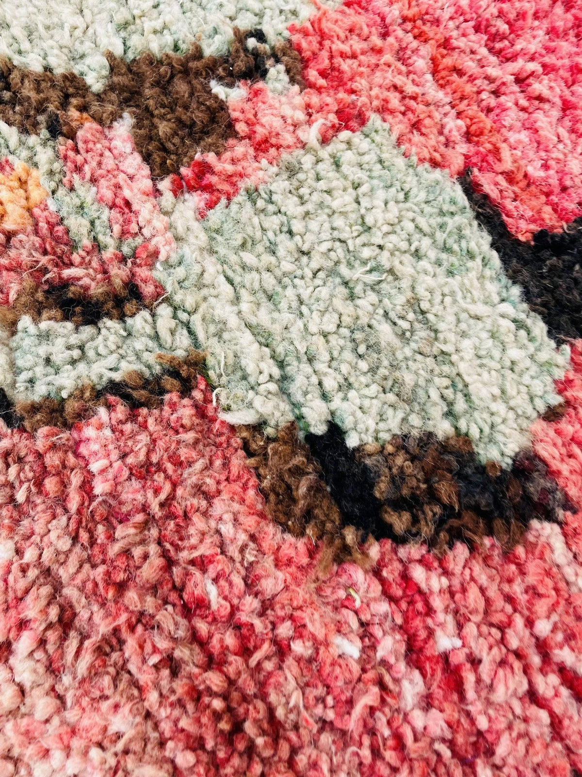 Close-up detail of a pink and white Moroccan rug featuring an abstract pattern.