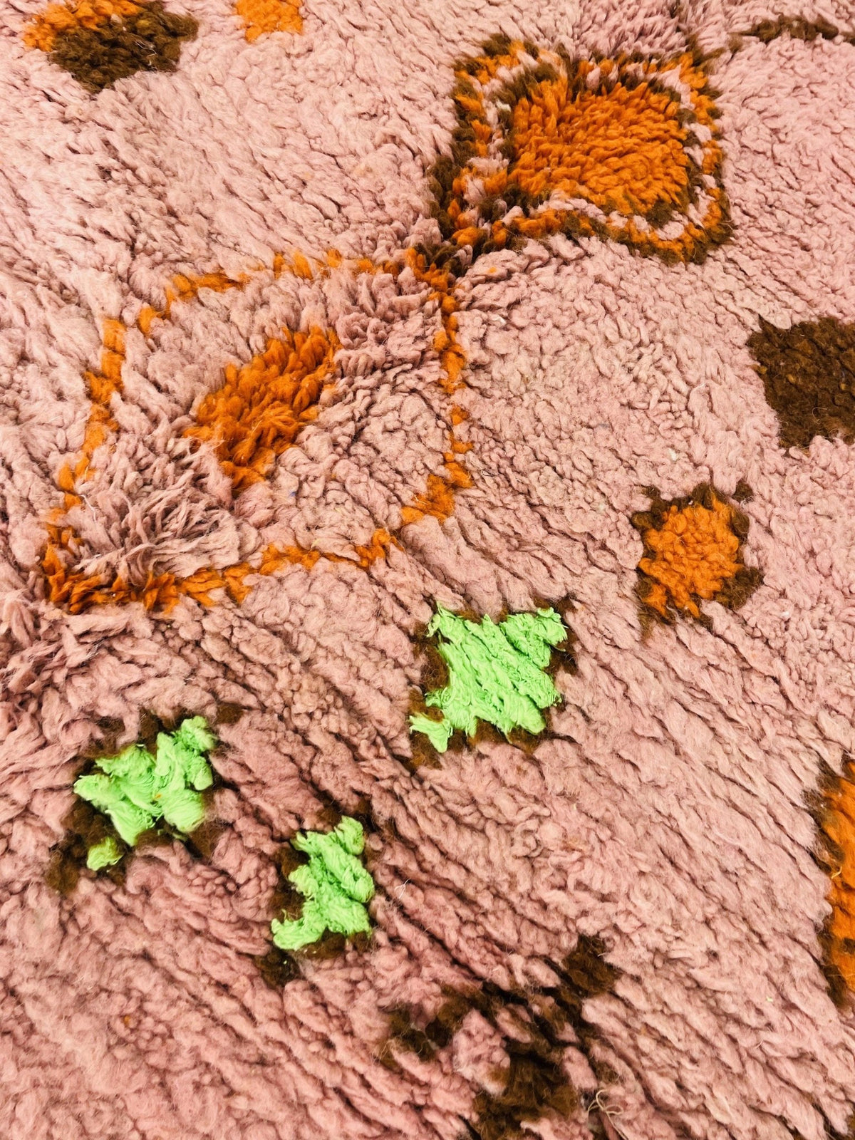 Detail view of the orange geometric Boujaad Moroccan rug showcasing abstract designs with pink and green tones.