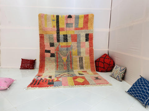 Lifestyle view of a pink abstract Boujaad Moroccan rug with fringe edges on a white background.