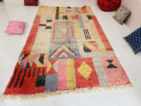 Lifestyle shot of a pink abstract Boujaad Moroccan rug featuring geometric patterns and fringe edges.