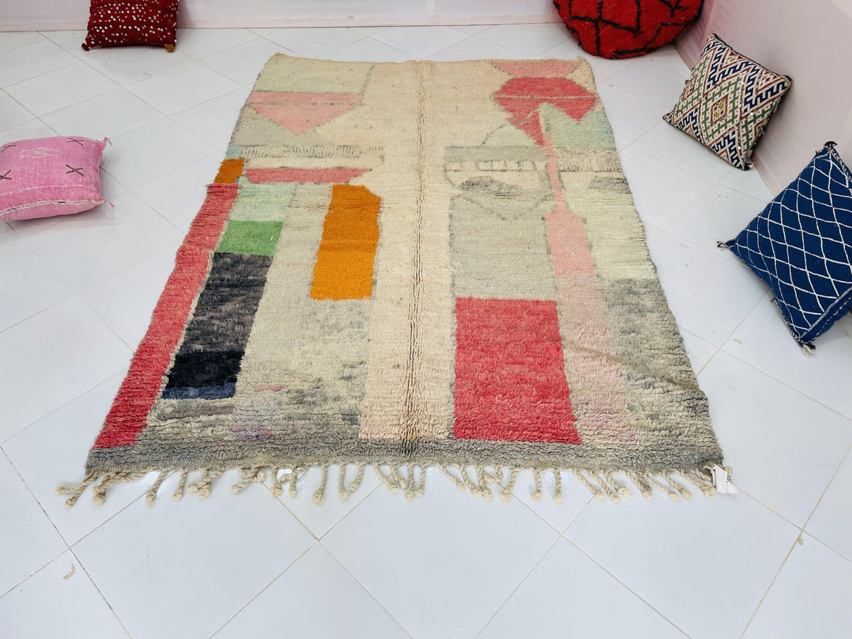 Front view of a pink abstract Moroccan rug featuring fringed edges and vibrant colors.