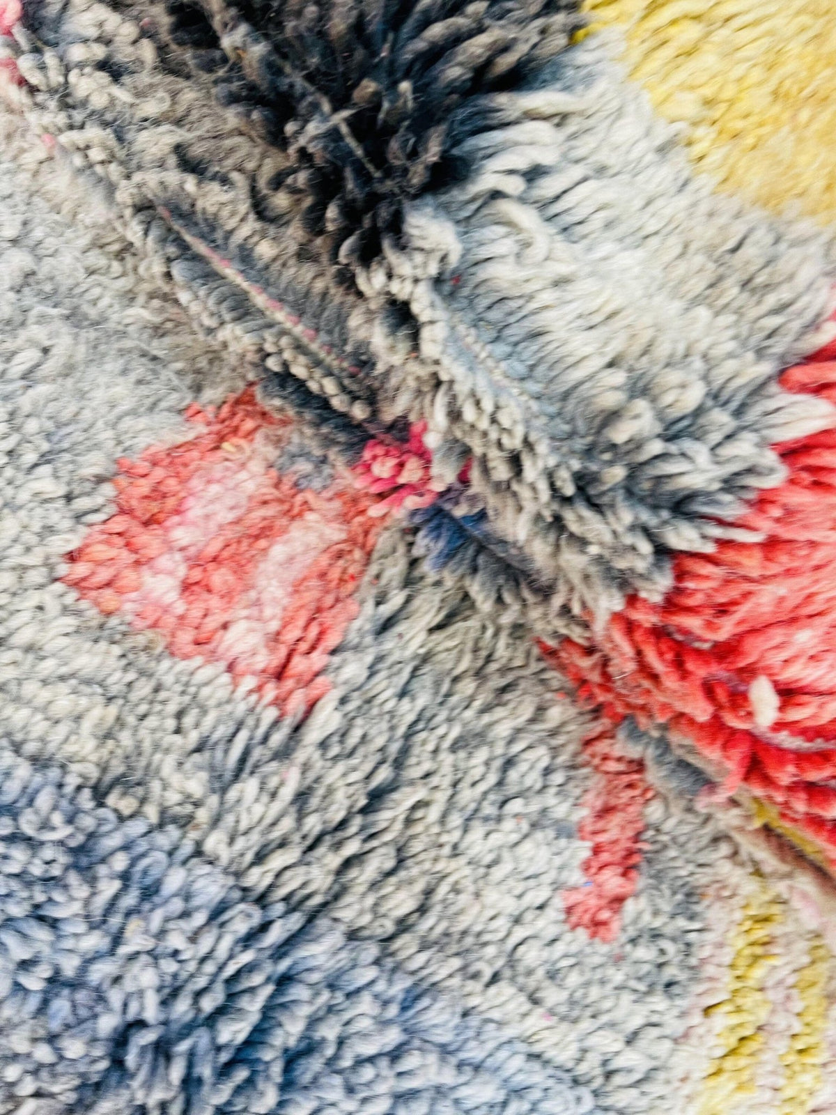 Close-up detail of the textured surface of a pink abstract Boujaad Moroccan rug with colorful fibers.