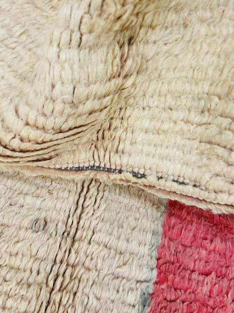 Top view of a pink abstract Moroccan rug showcasing its fringed edges and colorful design.