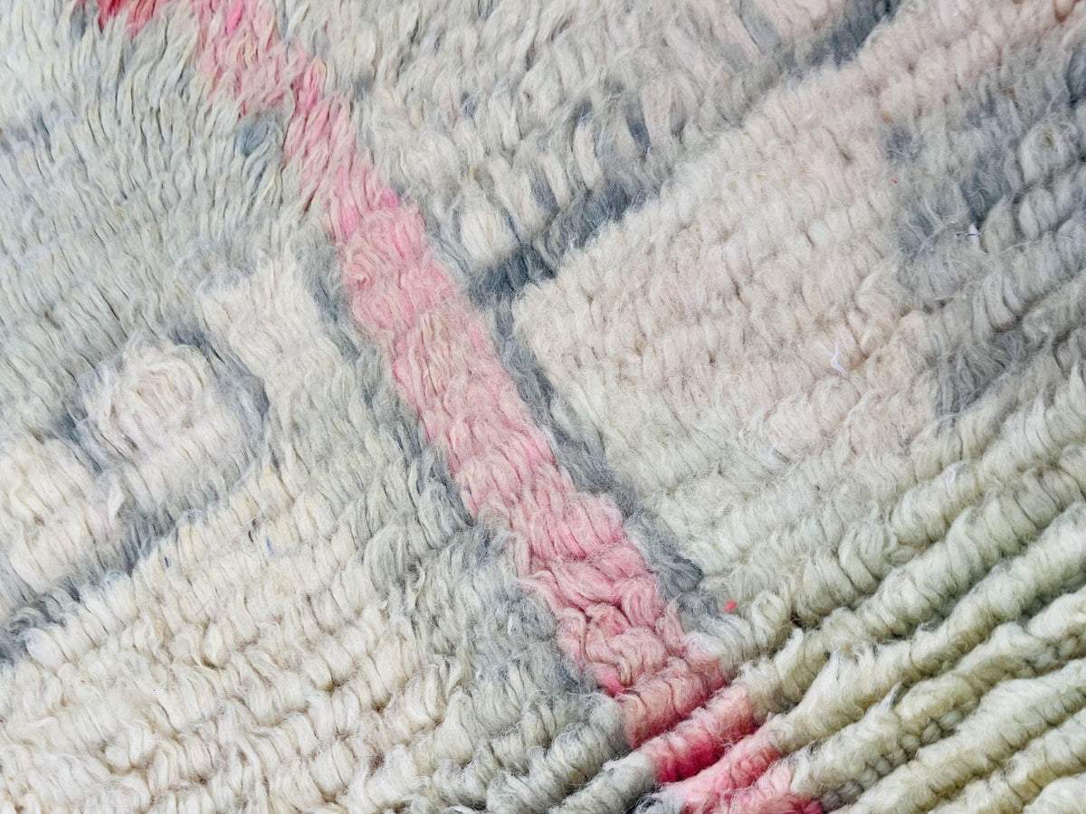 Close-up of a geometric design on a pink abstract Moroccan rug with a textured surface.