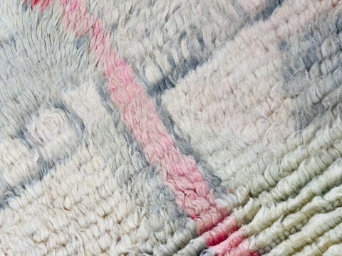Close-up of a geometric design on a pink abstract Moroccan rug with a textured surface.