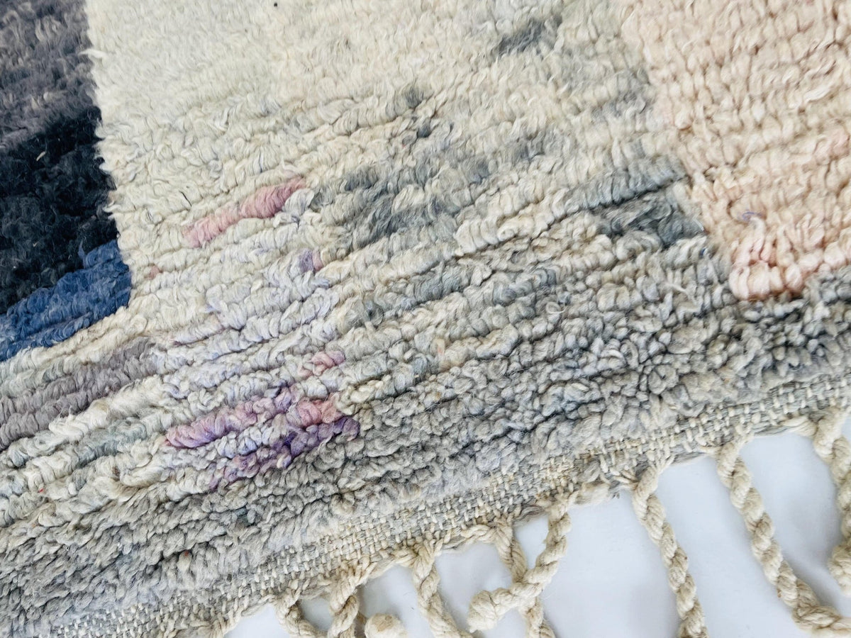 Close-up detail of the woven texture of a pink abstract Moroccan rug with color variations.