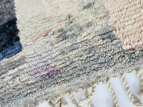 Close-up detail of the woven texture of a pink abstract Moroccan rug with color variations.