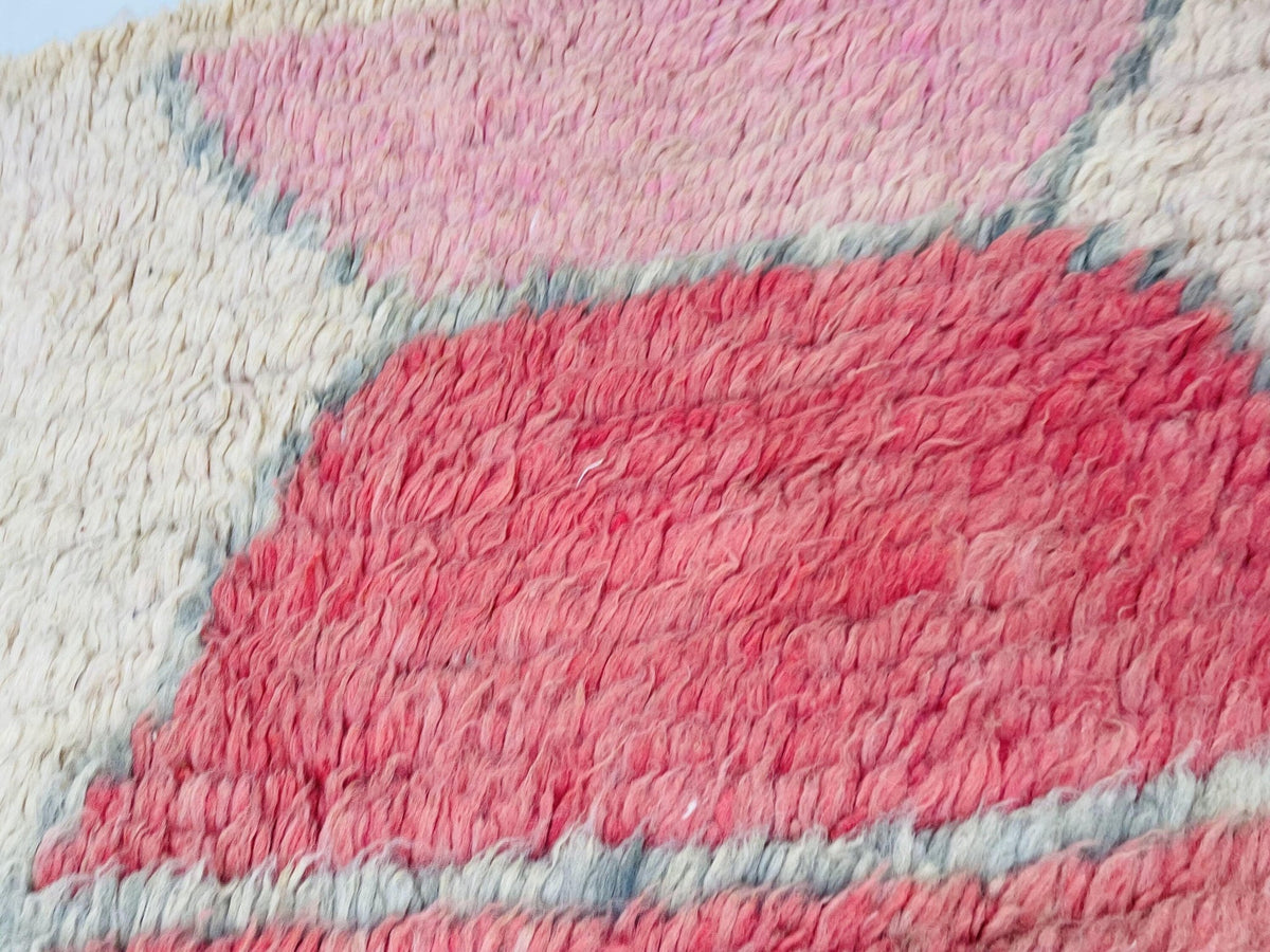 Detail shot of a pink and white abstract design on a Moroccan rug with a soft texture.