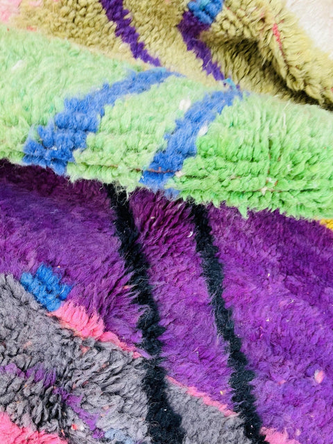 Lifestyle view of a purple and pink abstract Moroccan rug with colorful patterns.