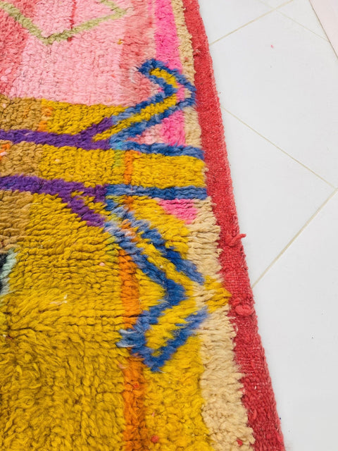 Close-up detail of a vibrant abstract pattern with red and pink on a Moroccan rug.
