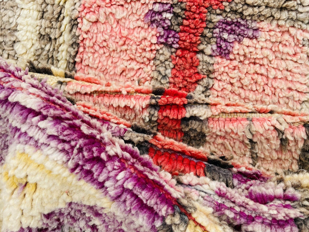 Front view of a red and pink abstract Moroccan rug on a white background.