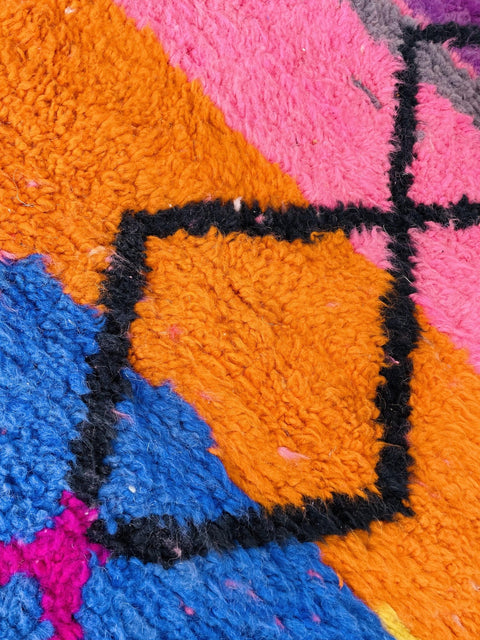 Detail shot of a geometric pattern in purple and pink on an abstract Moroccan rug.