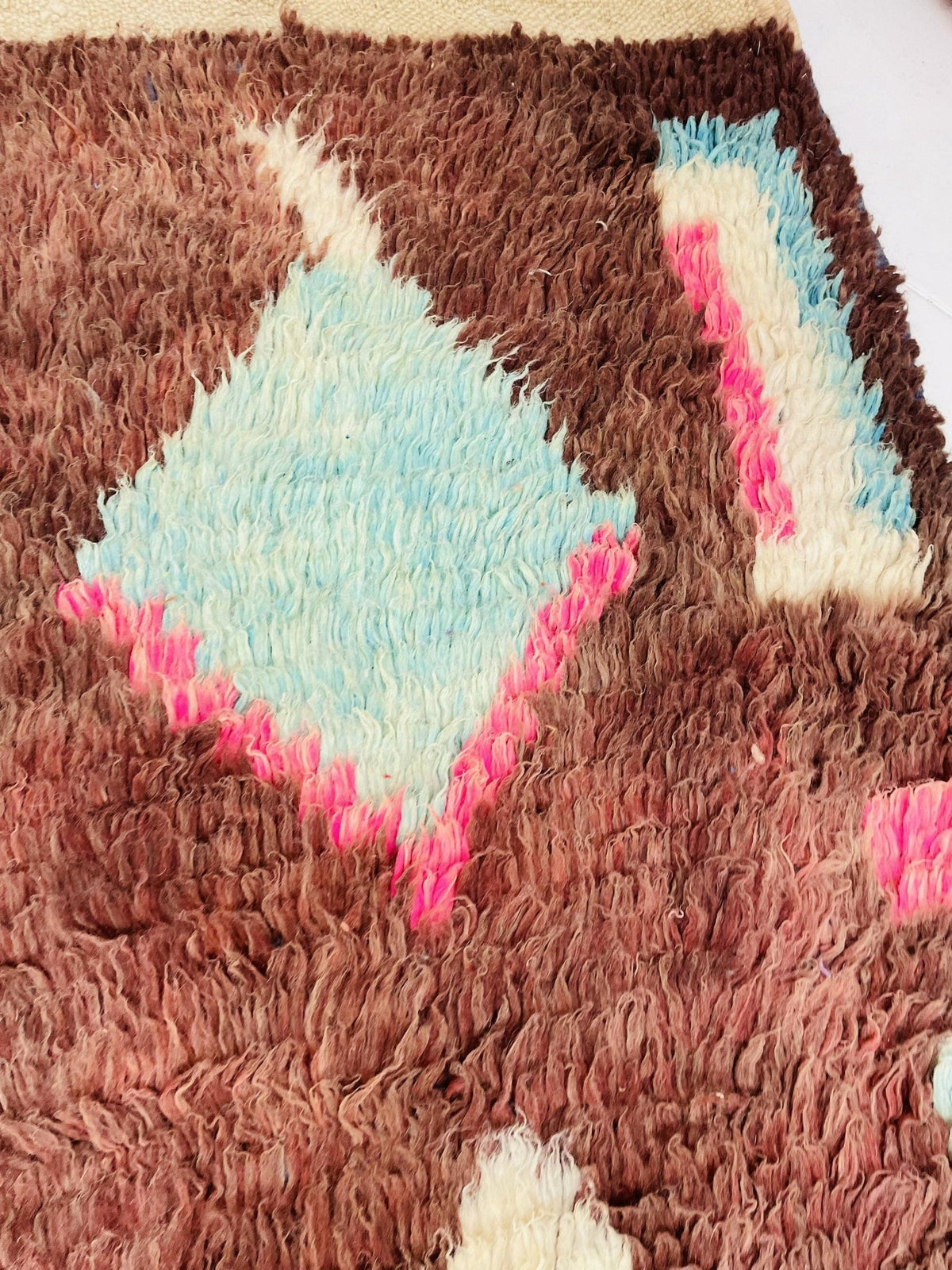 Detail view of a Boujaad Moroccan rug displaying diamond shapes in brown, pink, and cream.