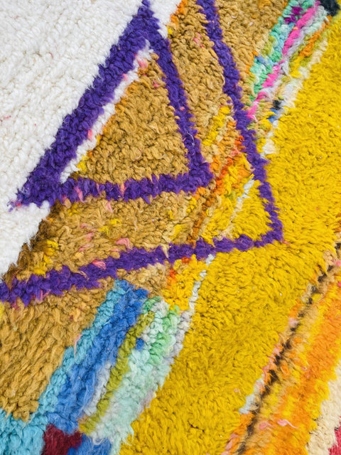 Detail view of a geometric design in yellow and purple on an abstract Moroccan rug.