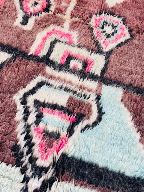 Close-up detail of a geometric Boujaad Moroccan rug featuring brown, pink, and blue colors.